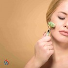 Vrouw die jade roller en gua sha stenen gebruikt